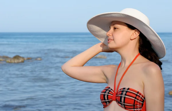 Das Mädchen mit dem Hut gegen das Meer und den blauen Himmel — Stockfoto