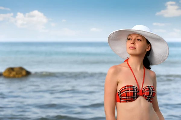 A menina em um chapéu contra o mar e céu azul — Fotografia de Stock