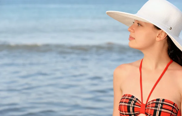 A menina em um chapéu contra o mar e céu azul — Fotografia de Stock