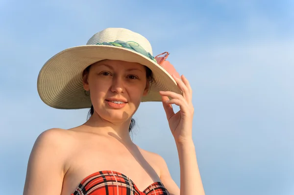Dívka v klobouku proti modré obloze — Stock fotografie