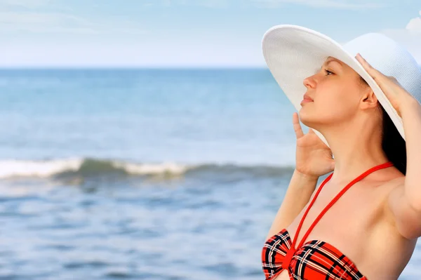 Het meisje in een hoed tegen de zee en de blauwe hemel — Stockfoto