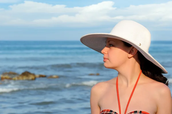 Das Mädchen mit dem Hut gegen das Meer und den blauen Himmel — Stockfoto