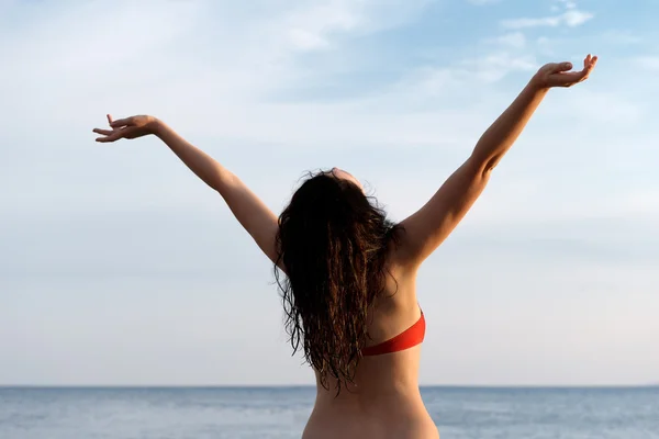 Девушка на берегу моря с поднятыми руками — стоковое фото