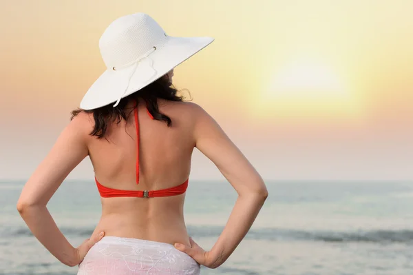 A mulher na costa do mar com um chapéu. Iluminação do pôr do sol . — Fotografia de Stock