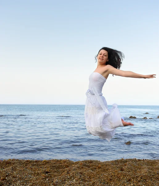 Den unga kvinnan hoppar på seacoast — Stockfoto