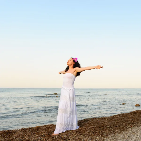 Kobieta w białą sukienkę na wybrzeże z otworzyć ręce — Zdjęcie stockowe