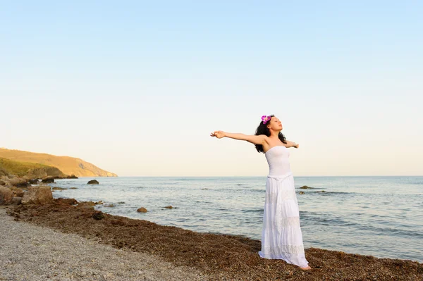 Žena v bílé letní šaty na mořského pobřeží s otevřít rukou — Stock fotografie