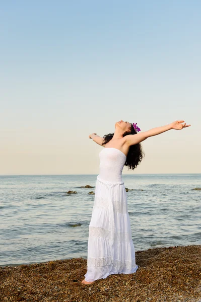 Женщина в белом сарафане на берегу моря с открытыми руками — стоковое фото