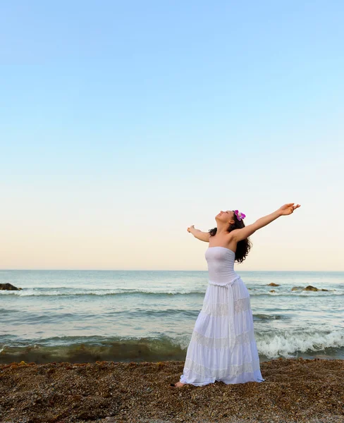 Kobieta w białą sukienkę na wybrzeże z otworzyć ręce — Zdjęcie stockowe