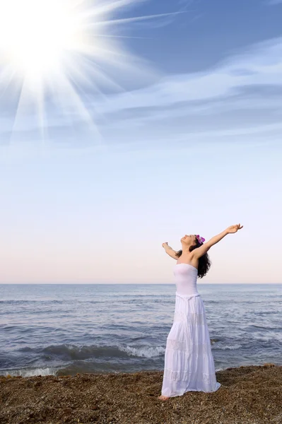 La femme dans une robe de soleil blanche sur le littoral avec les mains ouvertes — Photo