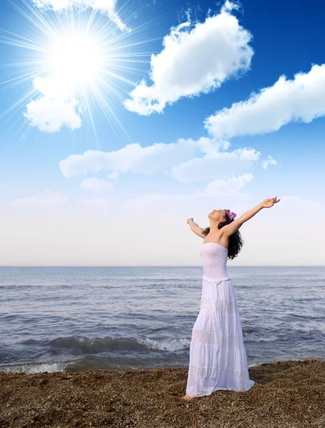 Die Frau im weißen Kleid am Ufer des Meeres mit offenen Händen — Stockfoto