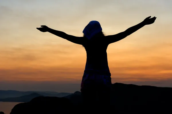 Die Frau auf einem Berg mit offenen Händen begrüßt einen Niedergang Stockbild