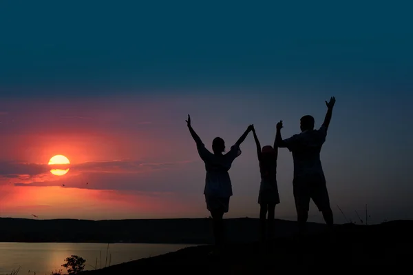 De familie van drie personen verwelkomt de zonsondergang zon — Stockfoto