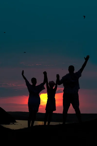 A család három személy üdvözli a naplemente nap — Stock Fotó