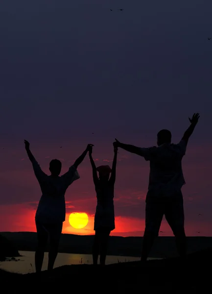 A família de três pessoas acolhe o pôr-do-sol — Fotografia de Stock