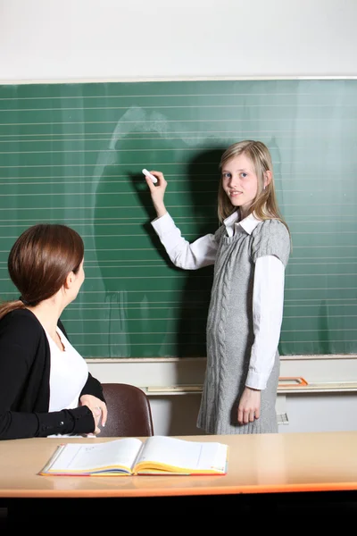Student in the classroom, writes on the blackboard. — Stock Photo, Image