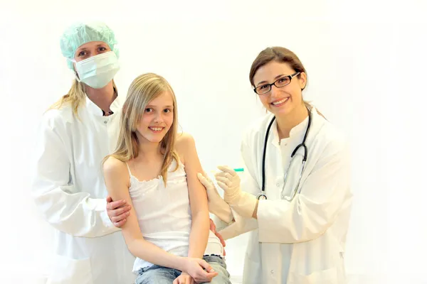 子供はチーム医者によって検査され、注射を与えられる — ストック写真