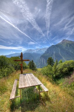 Wooden cross on alpine meadow. clipart