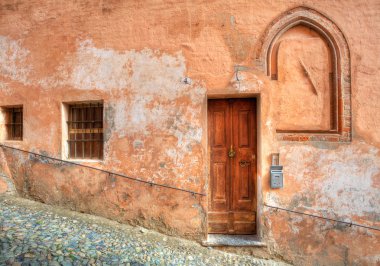Wooden door and small paved street in Saluzzo. clipart