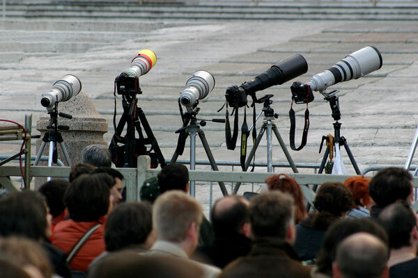 DSLR photo cameras with telephoto lenses on tripods.
