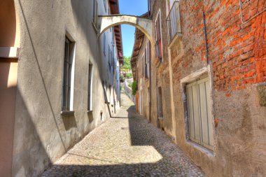 Old narrow street amont ancient houses in Avigliana, Italy. clipart