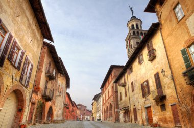 Paved street among historic houses in Saluzzo, Italy. clipart