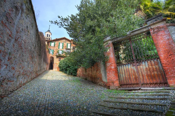 古い門、サルッツォ、イタリアの狭い舗装された道. — ストック写真