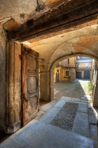 Oude deur en kleine werf in saluzzo, Italië. — Stockfoto