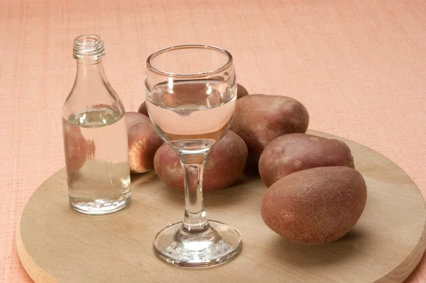 Aardappel wodka in een glas en een klein flesje — Stockfoto