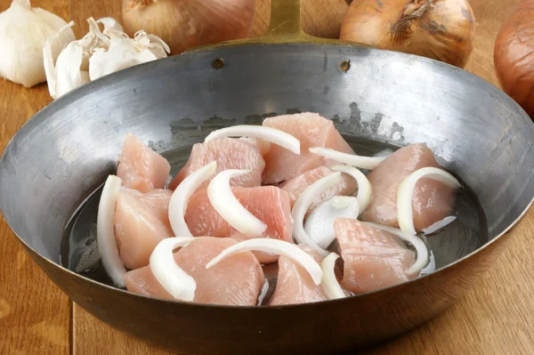 Diced chicken breast in an old brass pan — Stock Photo, Image