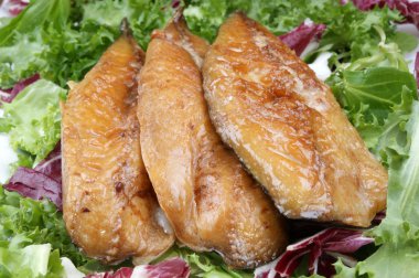 Smoked mackerel fillets on fresh organic lettuce clipart