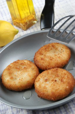 Three freshly fried fish cakes in a pan clipart