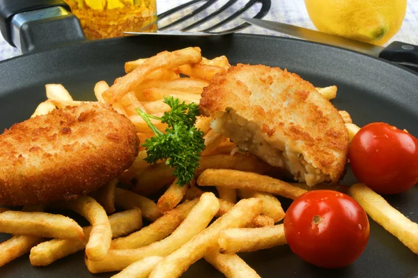 Fisk burgare med stekt chips på en stekpanna — Stockfoto