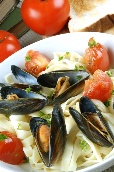 Pasta with mussels and grilled tomatoes on a plate — Stock Photo, Image
