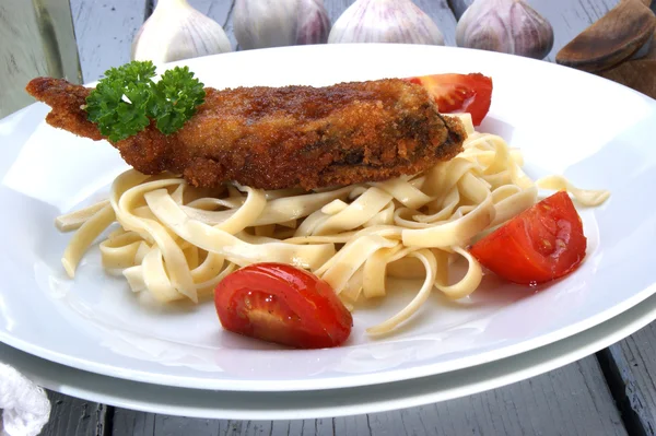 Breaded carp fillet with tomato on pasta — Stock Photo, Image