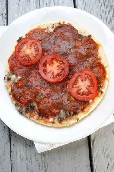 Salami pizza with tomato on a white plate — Stock Photo, Image