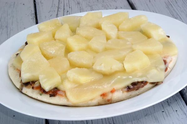 Pizza se sýrem a ananasem na bílé plotně — Stock fotografie