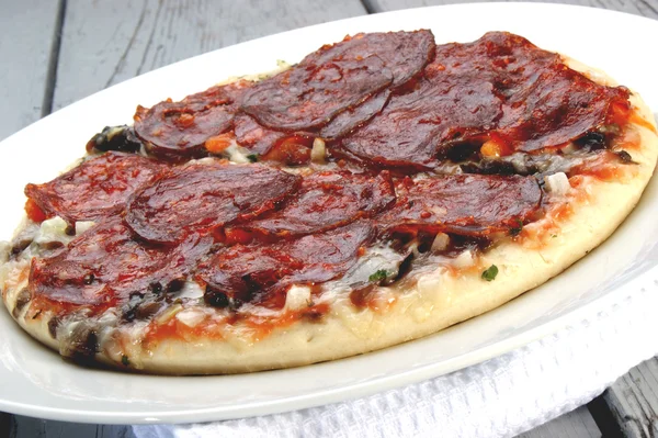 Pittige salami pizza op een witte plaat — Stockfoto