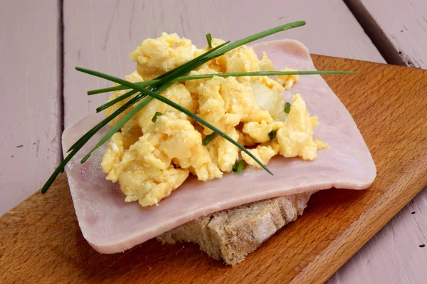 Çırpılmış yumurta ile chives ile pişmiş jambon ekmek üzerinde — Stok fotoğraf