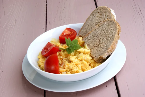 Scrambled eggs with tomato and bread in a white bowl — Stock Photo, Image
