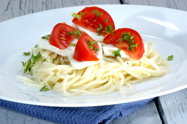 Mozzarella with tomatoes on home made spaghetti — Stock Photo, Image