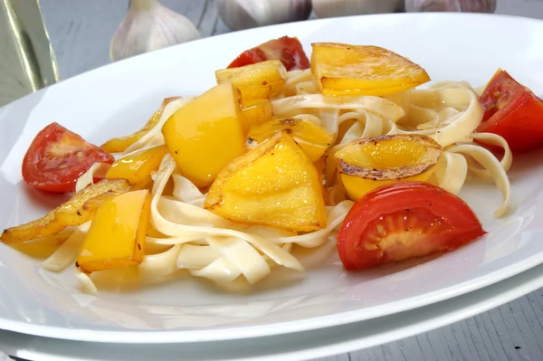 Gegrilde gele paprika's met tomaat op pasta — Stockfoto