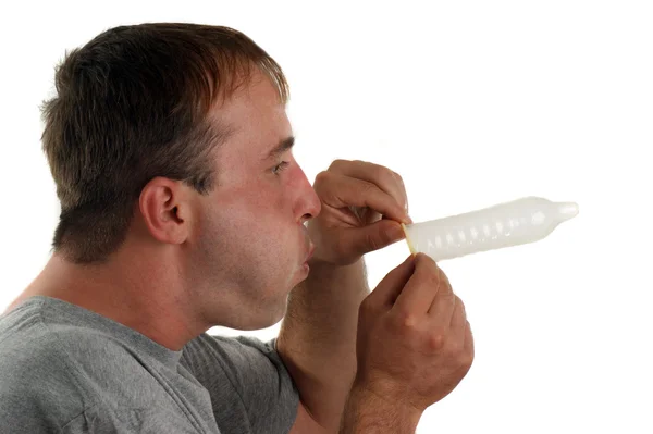 Jeune homme avec un T-shirt gris souffle dans un préservatif — Photo