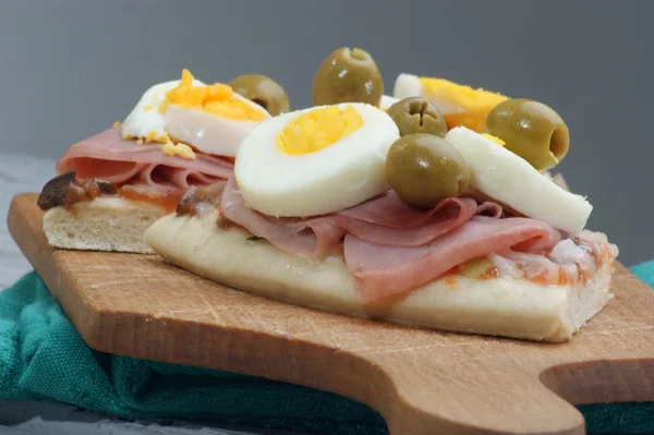Pizza com presunto e ovo em uma tábua de madeira — Fotografia de Stock
