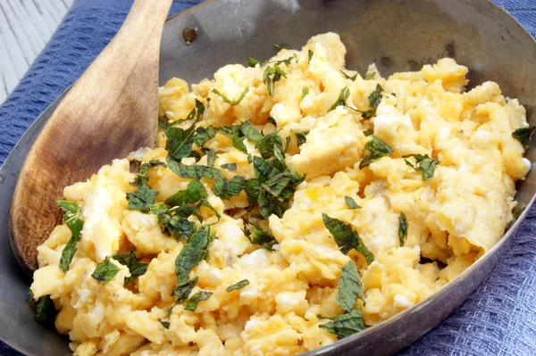 Scrambled eggs in a brass pan with chopped mint — Stock Photo, Image