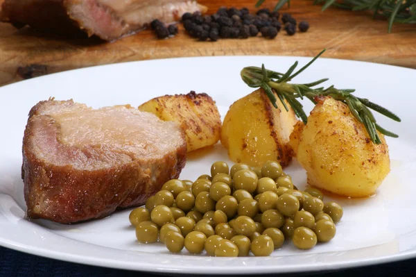 Rôti de porc avec pommes de terre rôties et petits pois — Photo