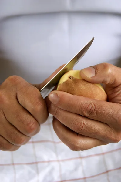 Eine Kartoffel wird mit einem Küchenmesser geschält — Stockfoto