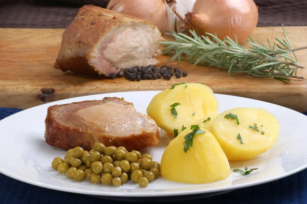 Porco assado com batatas assadas e ervilhas — Fotografia de Stock