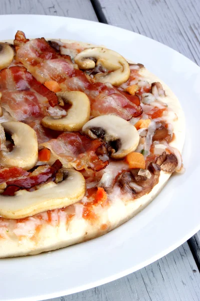 Pizza con pancetta e funghi su un piatto — Foto Stock