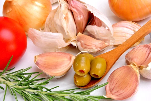 Olive su un cucchiaio di legno, aglio, cipolla e pomodoro — Foto Stock